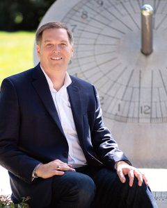 Peter Jessen seated beside a large stone sundial.